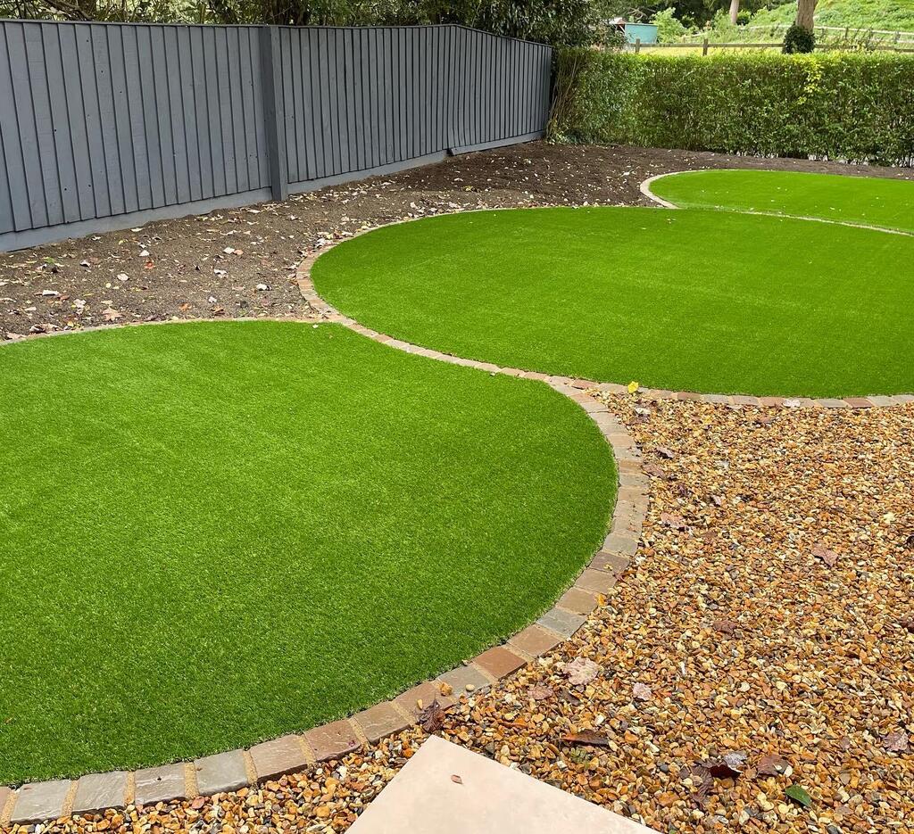 Exbury Bright Artificial Lawn with Multi-coloured cobbles around perimeter. 